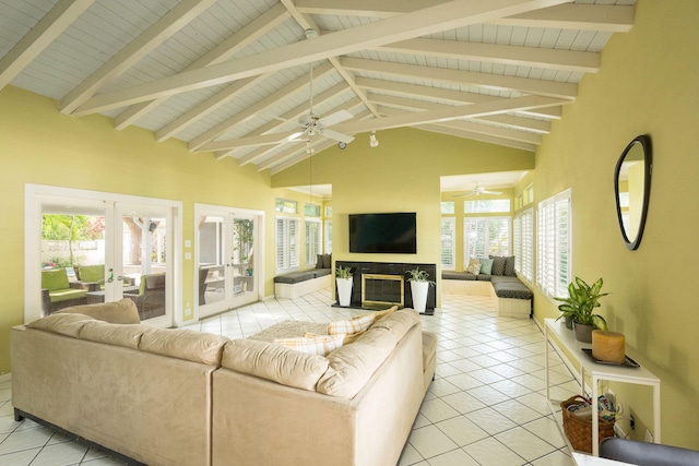 living area featuring light tile patterned floors, french doors, a glass covered fireplace, and beam ceiling