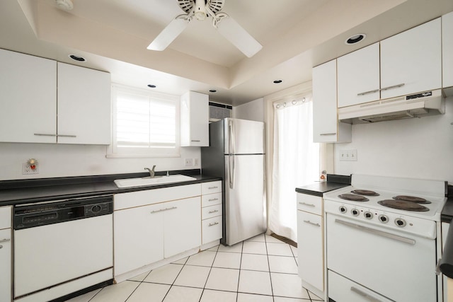 kitchen with dark countertops, white appliances, white cabinetry, and under cabinet range hood