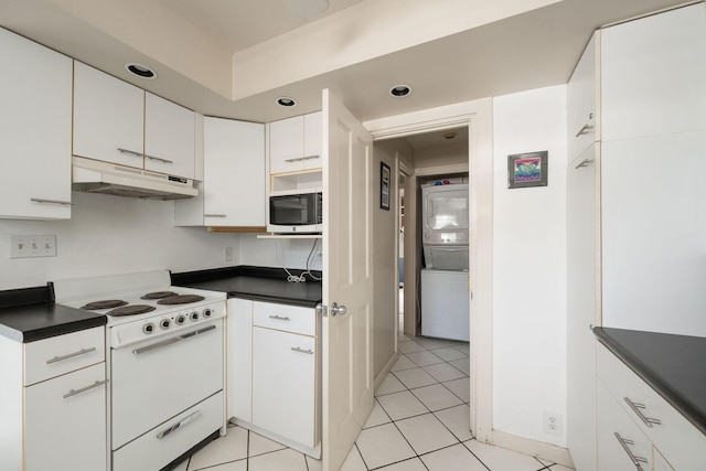 kitchen with under cabinet range hood, white cabinetry, stainless steel microwave, dark countertops, and white electric range oven