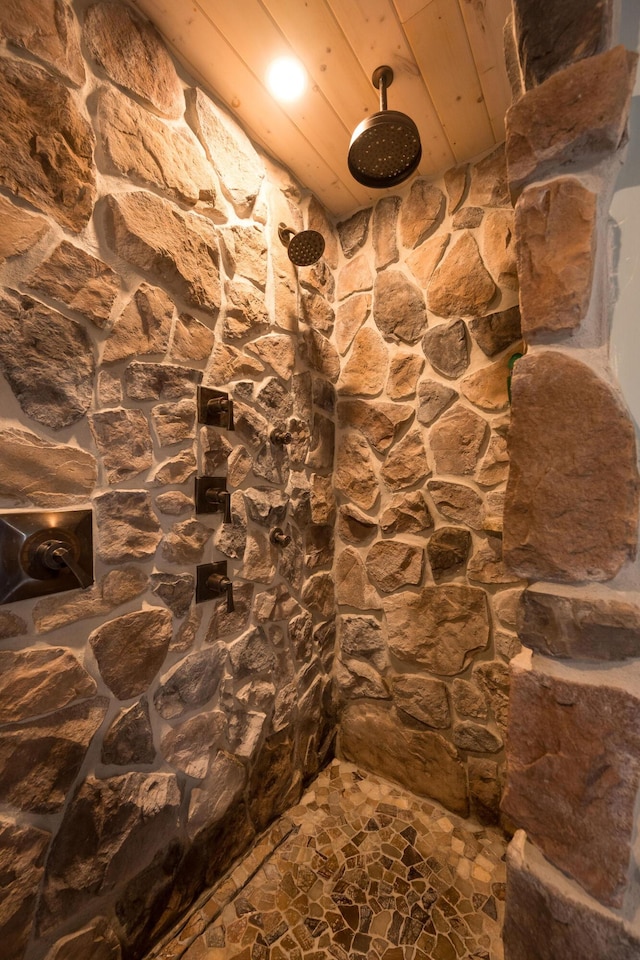 bathroom with stone finish flooring and tiled shower