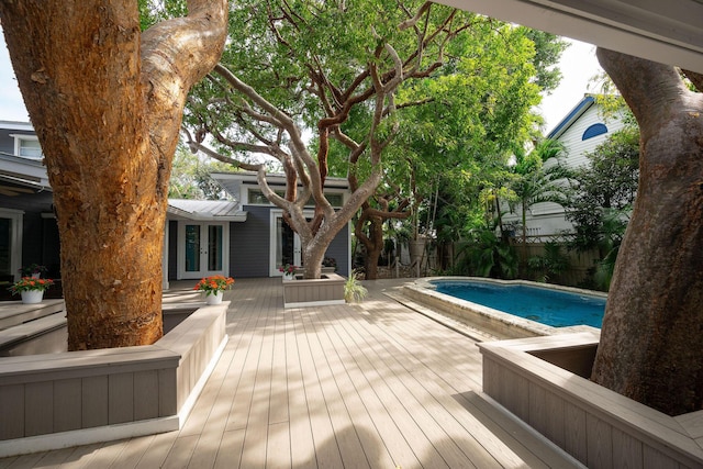 view of swimming pool featuring fence, a deck, a fenced in pool, and french doors