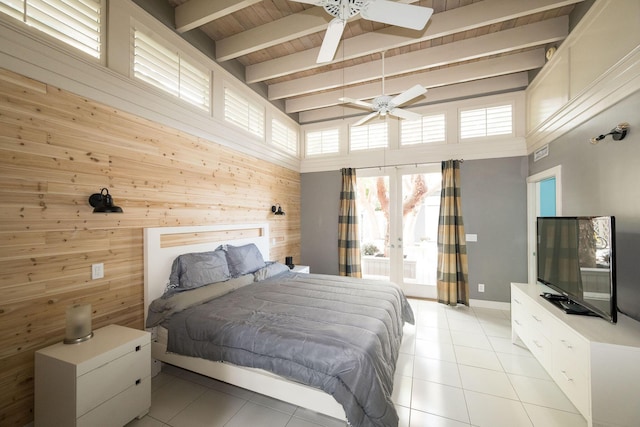 bedroom with light tile patterned floors, french doors, beam ceiling, and wooden walls