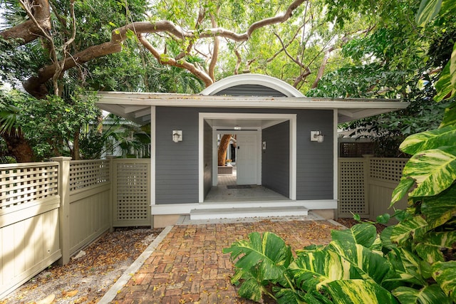 view of exterior entry featuring fence and metal roof