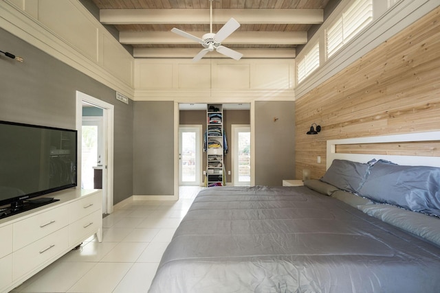 unfurnished bedroom with light tile patterned floors, beamed ceiling, multiple windows, and wooden walls