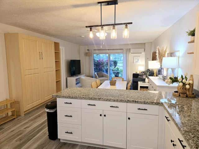 kitchen with light stone counters, pendant lighting, white cabinetry, and open floor plan