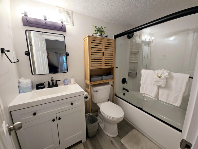 bathroom with shower / bath combination with glass door, toilet, vanity, a textured ceiling, and wood finished floors