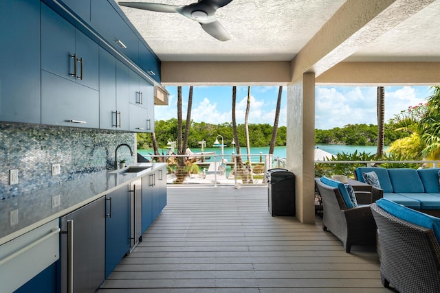deck featuring a sink, a water view, a ceiling fan, and an outdoor living space