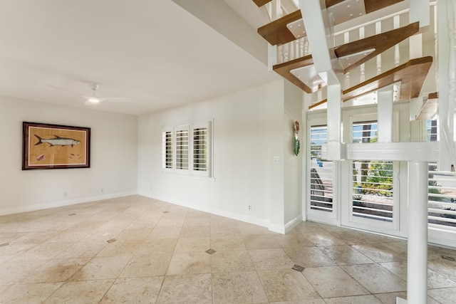 empty room with baseboards, ceiling fan, and tile patterned flooring