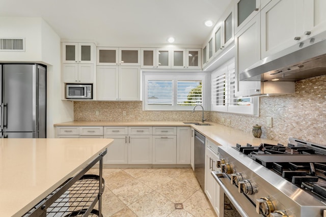 kitchen with stainless steel appliances, under cabinet range hood, light countertops, a sink, and white cabinets