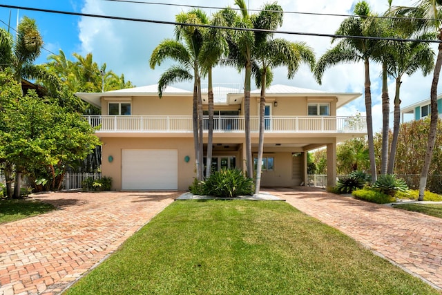 view of front of property featuring decorative driveway, an attached garage, stucco siding, and a balcony