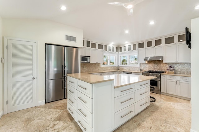 kitchen featuring appliances with stainless steel finishes, under cabinet range hood, a center island, glass insert cabinets, and recessed lighting