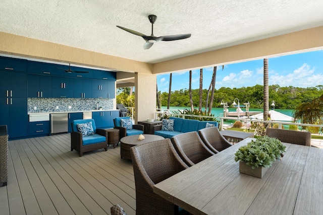 wooden deck with ceiling fan, an outdoor hangout area, area for grilling, and view of wooded area