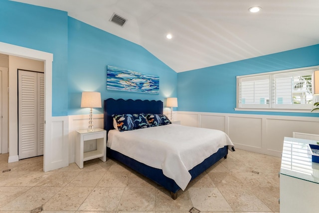 bedroom featuring vaulted ceiling, wainscoting, a decorative wall, and recessed lighting