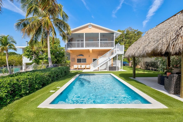 rear view of house featuring fence, stairs, a lawn, a fenced in pool, and a patio area