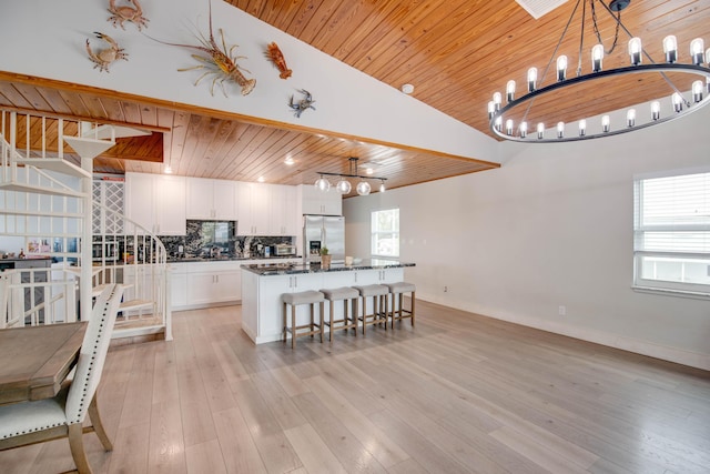 kitchen featuring white cabinetry, wood ceiling, stainless steel fridge with ice dispenser, hanging light fixtures, and a kitchen island