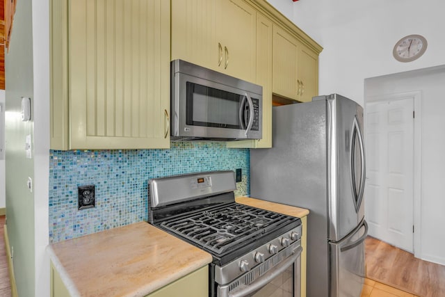 kitchen with appliances with stainless steel finishes, light hardwood / wood-style floors, and decorative backsplash
