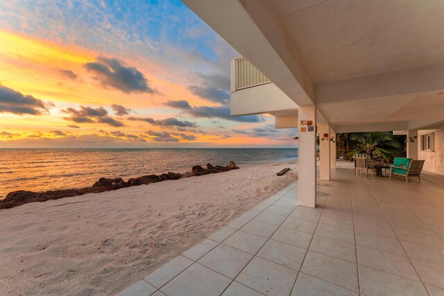 patio terrace at dusk with a beach view and a water view