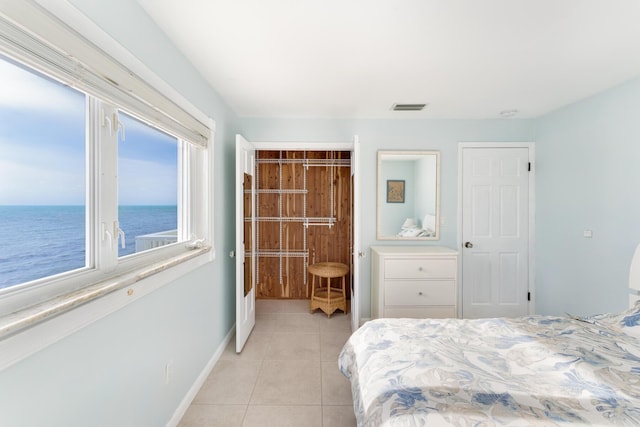 bedroom featuring light tile patterned floors and a water view