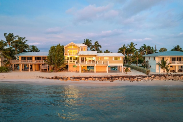 rear view of property featuring a water view, a balcony, and a view of the beach