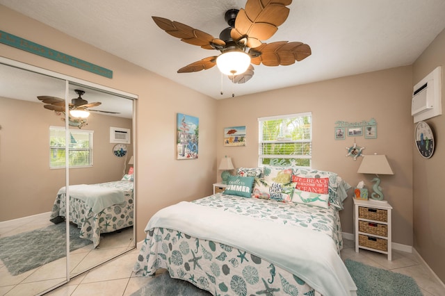 tiled bedroom featuring a wall mounted AC, ceiling fan, and a closet