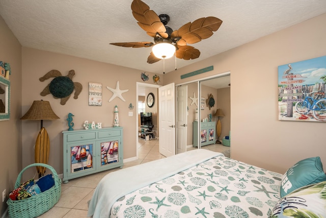 tiled bedroom with ceiling fan, a closet, and a textured ceiling