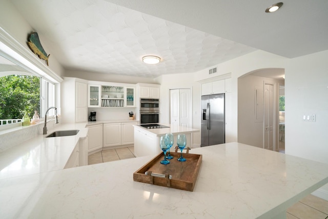 kitchen featuring stainless steel appliances, a center island, sink, and white cabinets