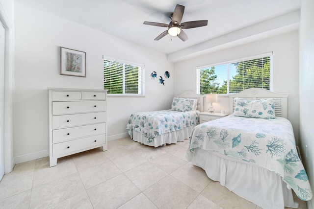 bedroom featuring ceiling fan, multiple windows, and light tile patterned floors