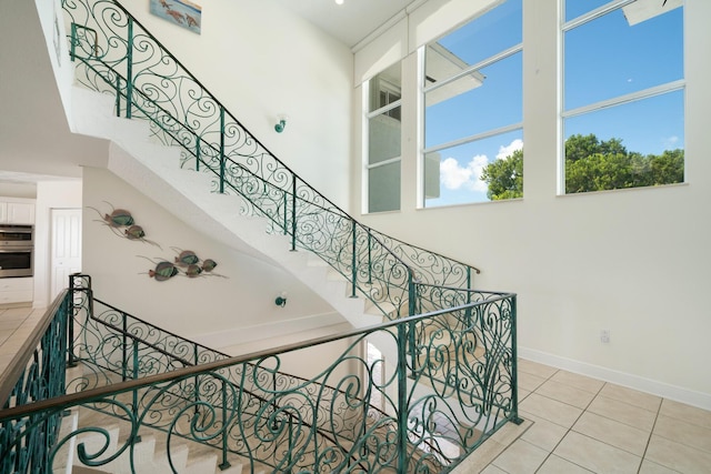 stairway featuring a high ceiling and tile patterned floors