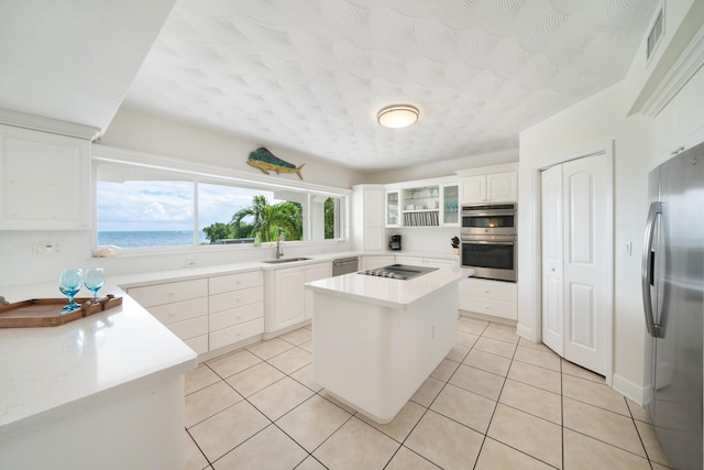 kitchen with sink, a water view, a center island, appliances with stainless steel finishes, and white cabinets