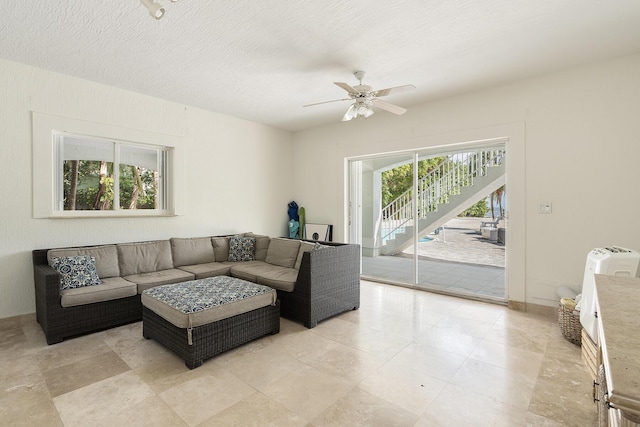 living room featuring ceiling fan and a textured ceiling