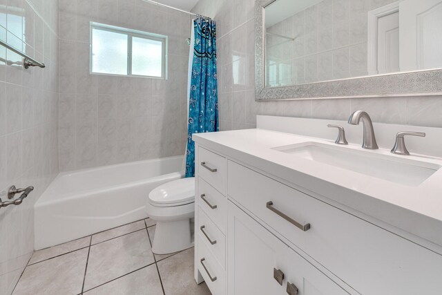 full bathroom with shower / tub combo with curtain, tile patterned flooring, tile walls, vanity, and toilet