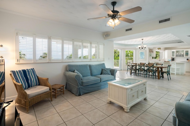 tiled living room with ornamental molding, a tray ceiling, and ceiling fan with notable chandelier