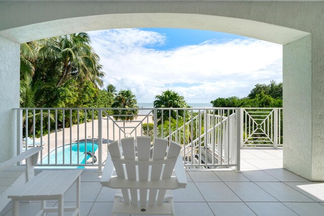 view of patio featuring a water view, a balcony, and a fenced in pool