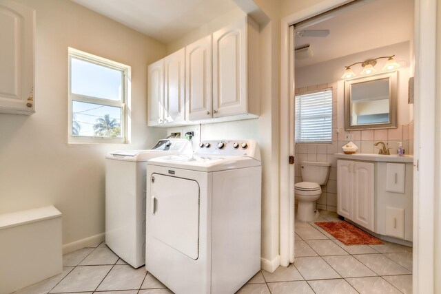 clothes washing area with plenty of natural light, washer and dryer, light tile patterned floors, and sink