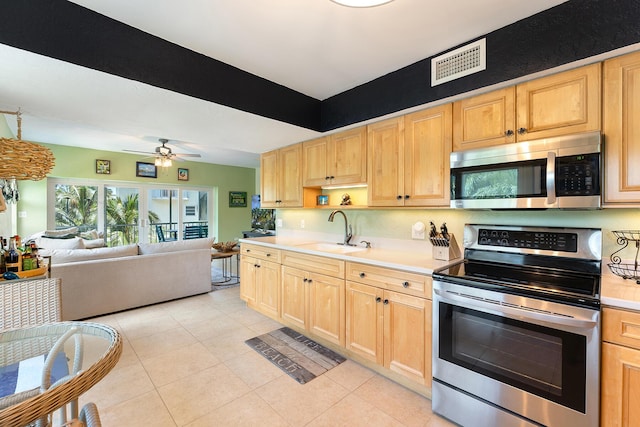 kitchen featuring stainless steel appliances, sink, light tile patterned floors, and light brown cabinetry