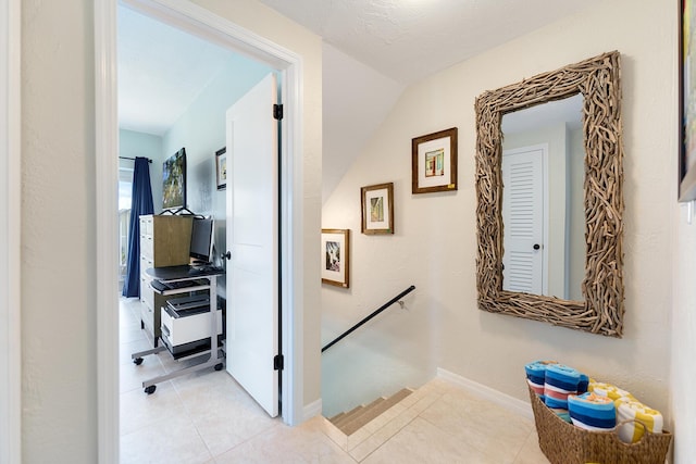 corridor featuring light tile patterned floors and a textured ceiling