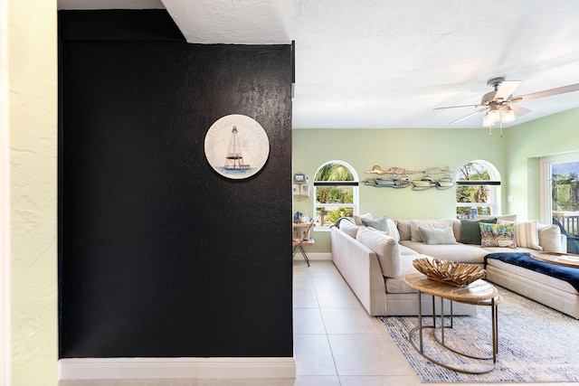 living room featuring light tile patterned floors, a textured ceiling, and ceiling fan