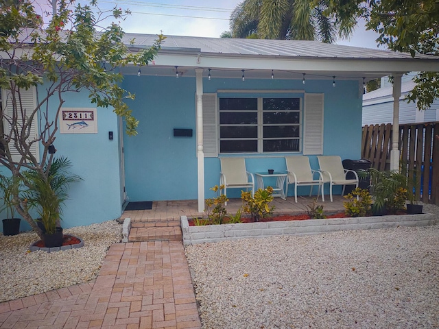 view of front facade featuring stucco siding, a porch, and fence