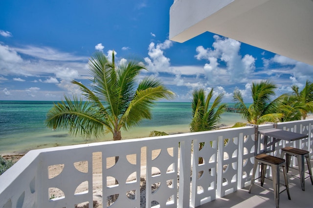 balcony with a water view and a view of the beach