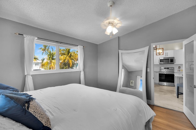 bedroom with a textured ceiling, a ceiling fan, and light wood finished floors