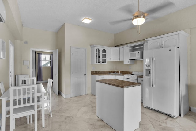 kitchen featuring white appliances, a ceiling fan, a sink, white cabinetry, and a center island