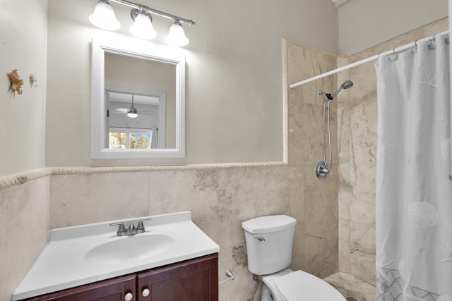 full bathroom with wainscoting, tiled shower, toilet, and vanity