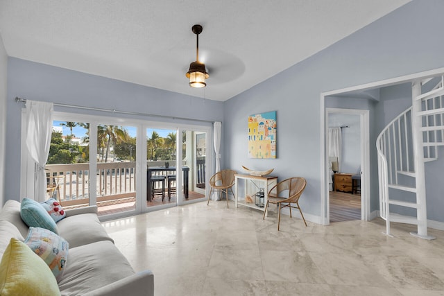 living room featuring a ceiling fan, stairs, baseboards, and vaulted ceiling