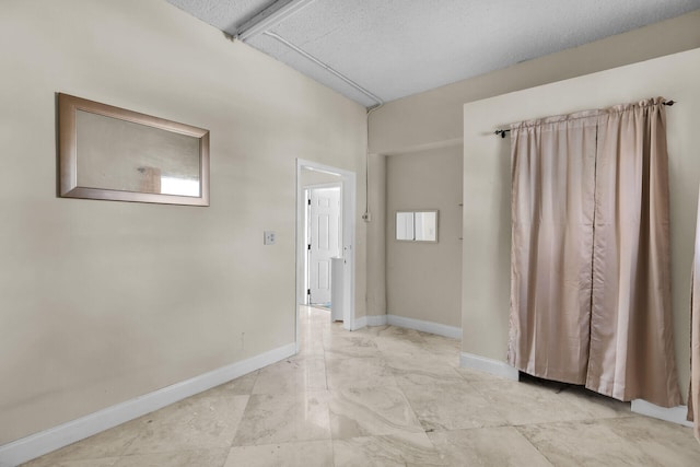 unfurnished room with a textured ceiling and baseboards