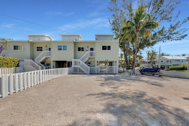 rear view of property featuring stairway and fence