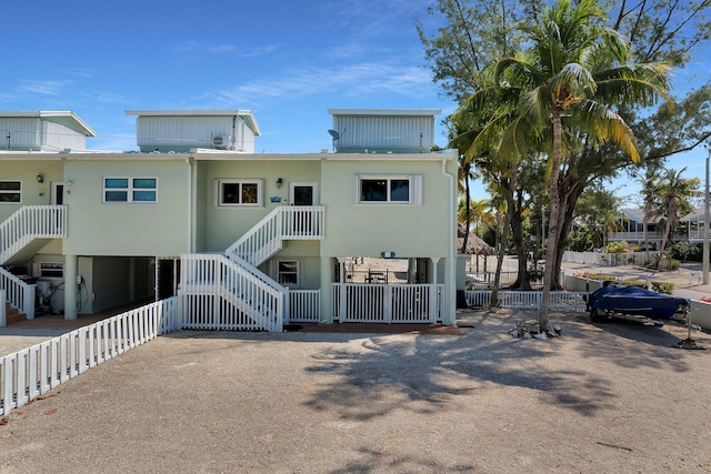 view of front of property with stairs, fence, and stucco siding