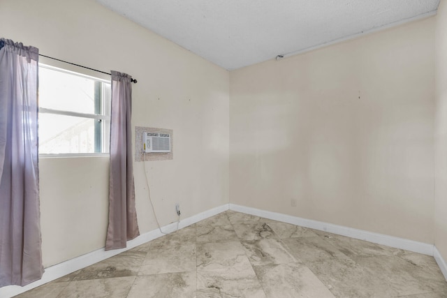 empty room with an AC wall unit and baseboards