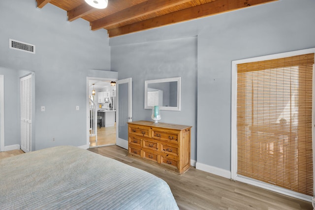 bedroom featuring light wood finished floors, visible vents, baseboards, beam ceiling, and wooden ceiling