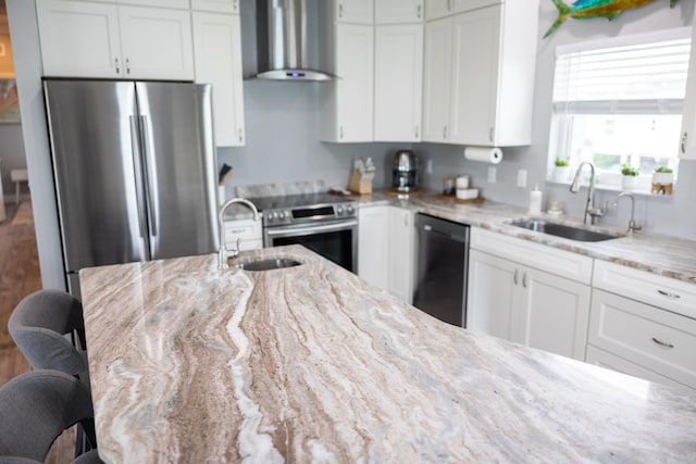 kitchen with light stone countertops, sink, a kitchen breakfast bar, and wall chimney exhaust hood