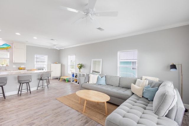 living room featuring ornamental molding, light hardwood / wood-style floors, and ceiling fan